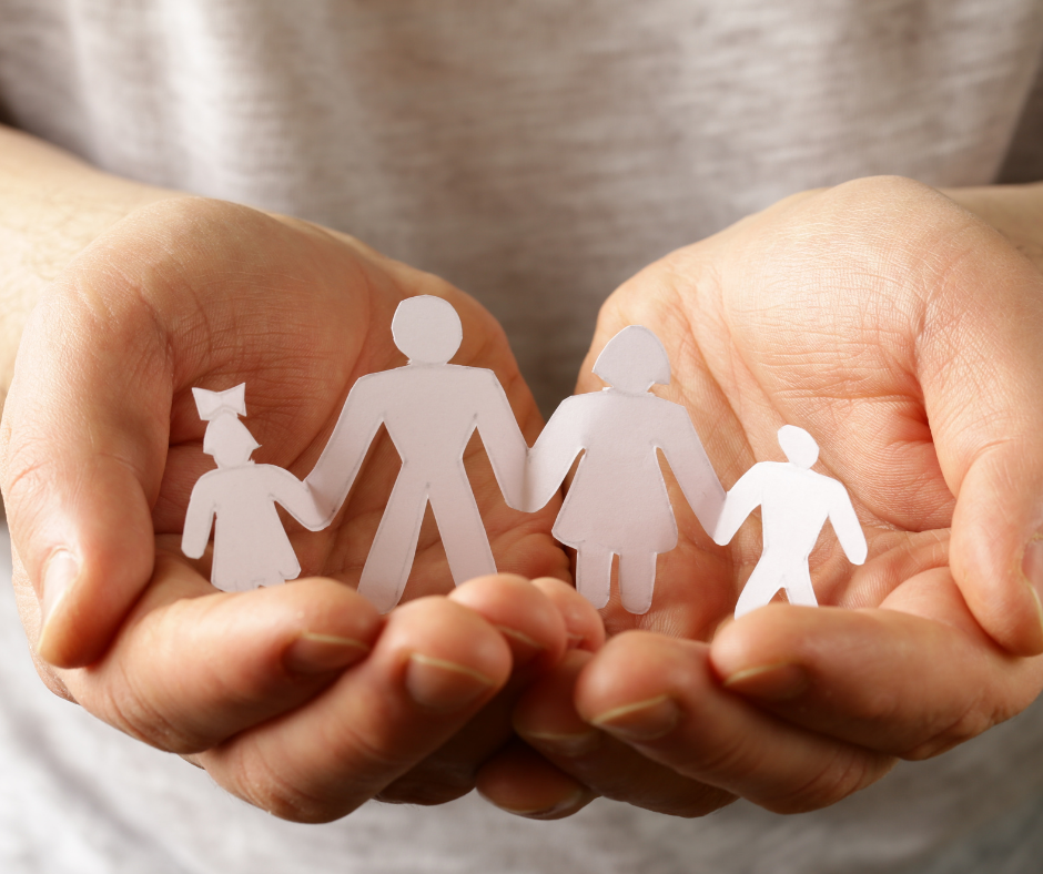 An image of hands holding a white paper cutout of parents and children