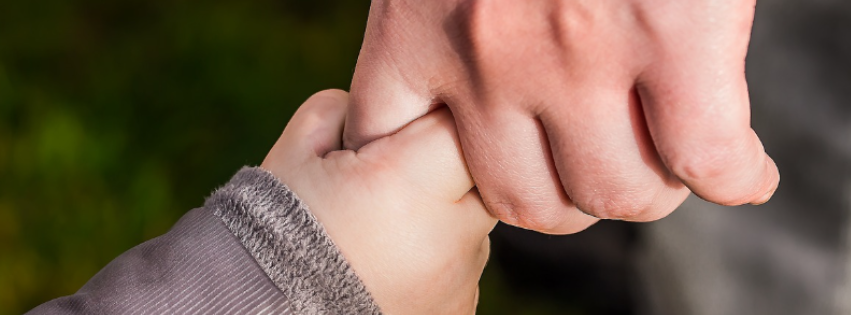 Child holding an adults finger